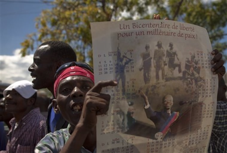 A man holds a calendar depicting Haiti's ousted President Jean-Bertrand Aristide during a protest in Port-auPrince, Haiti, Friday, Feb. 18, 2011. A few thousand supporters of Aristide marched through Haiti's capital Friday shouting they will derail a presidential runoff set for next month unless his leader returns. (AP Photo/Ramon Espinosa)